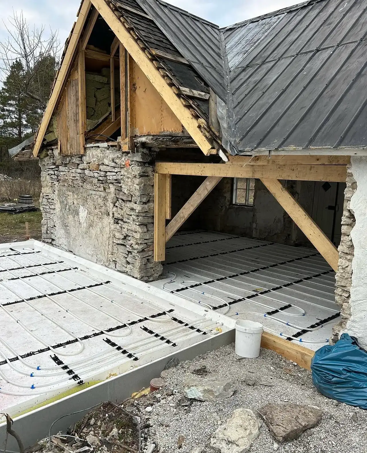 Person installerar röda vattenburna golvvärmerör på byggplats.